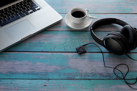 笔记本电脑、耳机、音乐播放器、蓝木桌上的黑咖啡