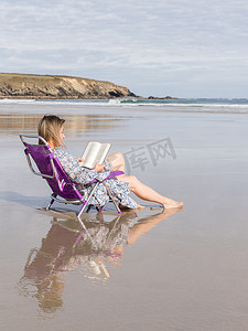 书的海洋摄影照片_坐在海滩椅子上看书的女人