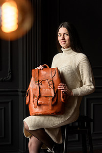照片中，一位女士背着橙色皮革背包，具有古董和复古的外观。