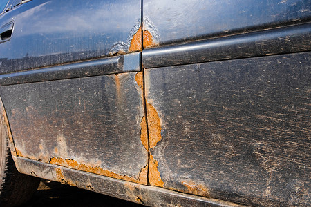 一辆肮脏受损汽车的金属门上有锈迹。