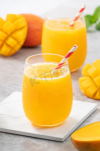 灰色桌子背景的玻璃杯中的新鲜芒果汁冰沙。