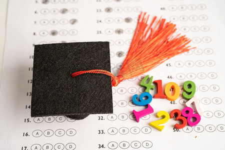 毕业间隙帽子和铅笔在答卷背景上，教育研究测试学习教学概念。