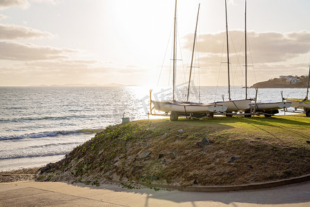 清晨的阳光穿过海洋照在停泊的帆船上