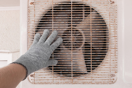 空调维修和保养专家的手，戴着建筑手套，与空调旧设备一起工作