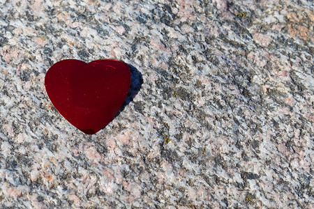 浪漫的红色爱心躺在详细的花岗岩背景上
