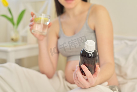 孕妇生病摄影照片_年轻孕妇手里拿着可溶性药物、维生素