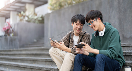 快乐的亚洲男大学生与朋友在智能手机上玩手机游戏