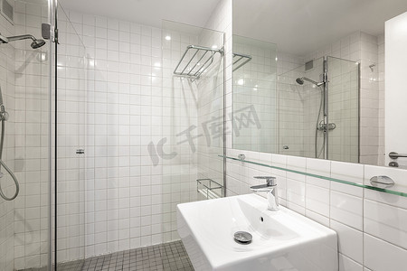舒适简洁的浴室配有白色瓷砖、水槽和玻璃淋浴间。