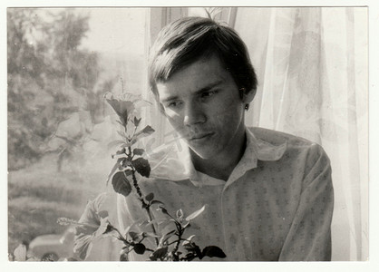 老式照片显示一个十几岁的男孩拿着花。