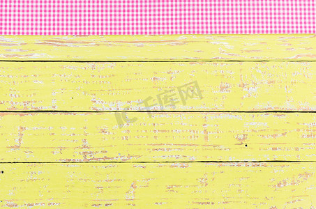 黄色木桌面背景纹理，配有质朴的粉色桌布
