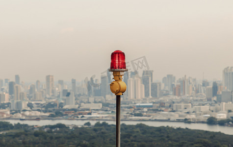 高层建筑屋顶安装障碍灯红灯笼，确保飞行安全，并在城市景观背景下警告飞机危险。