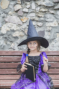 年轻女巫用魔杖和咒语书思考