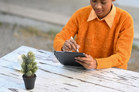 互联网信息摄影照片_年轻女性在休息期间在咖啡馆工作并在数字平板电脑上搜索互联网信息的剪影
