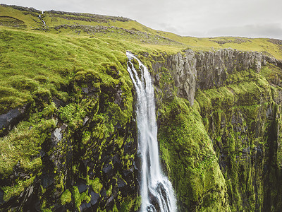 冰岛瀑布顶部的鸟瞰图，覆盖着青苔覆盖的岩石
