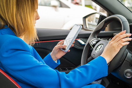 汽车智能驾驶摄影照片_女人开车并使用她的智能手机