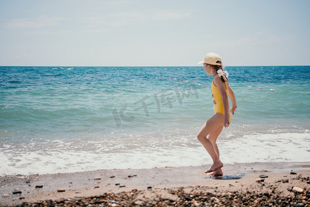 可爱的小女孩沿着海边奔跑，映衬着清澈的蓝色大海，在夏日的阳光下欢欣鼓舞。