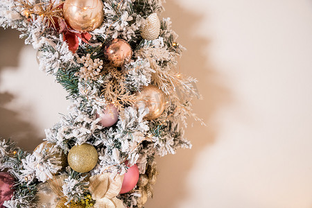 圣诞花环由挂在米色墙上的天然冷杉树枝制成。