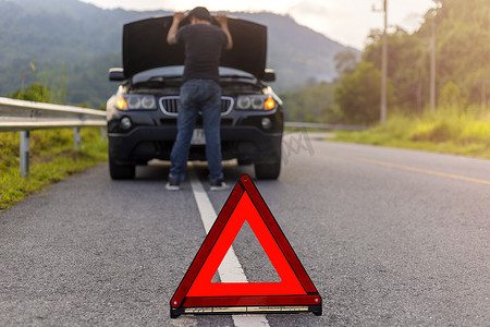 道路上的红色三角标志警告有带故障操作的汽车