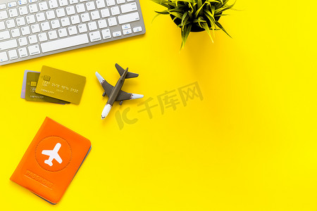 旅行计划 — 护照、键盘、飞机 — 在黄色桌子上自上而下的复印空间