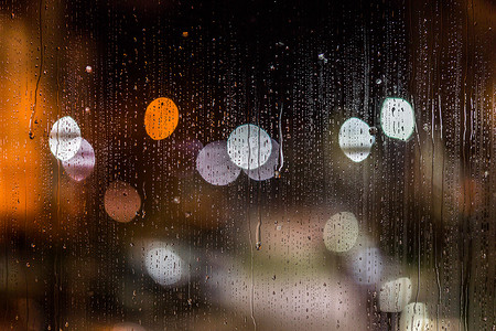 透过摄影照片_抽象的背景夜路灯透过湿玻璃和水渍散景，特写有选择的焦点