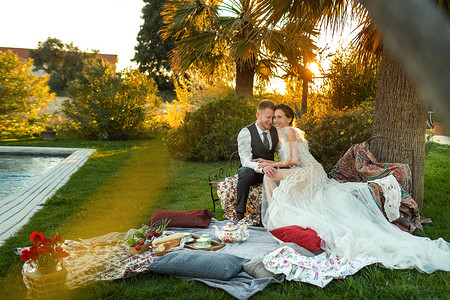 新婚夫妇在日落时分在草坪上共进晚餐。法国日落时分，一对夫妇坐在一起喝茶