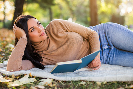 女人在公园看书，在秋天享受