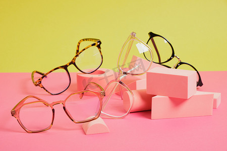 几何粉色讲台上的时髦眼镜，彩色背景，复制空间