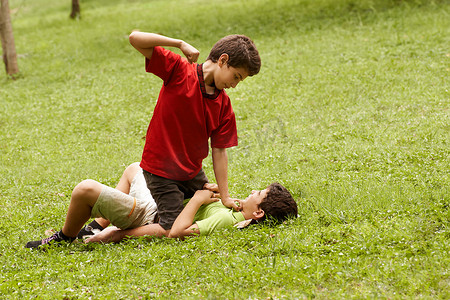 哭泣摄影照片_暴力的孩子在公园里打架并殴打害怕的男孩