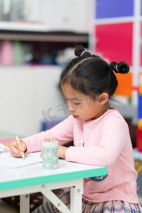 可爱的亚洲泰国小女孩坐着画作业