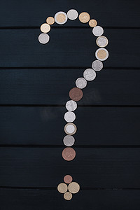 木桌上以问号点的形式散落着不同国家的硬币。
