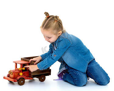 一辆火车摄影照片_小女孩正在玩一辆木制汽车。