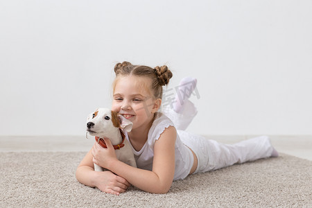 人、儿童和宠物的概念 — 小女孩和可爱的小狗杰克罗素梗犬躺在地板上