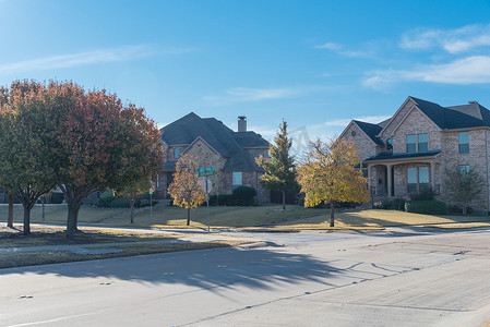 美国得克萨斯州达拉斯附近的人行道上有一排郊区房屋和色彩缤纷的秋叶的相当新的开发区