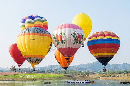 2017 年泰国清莱省 Singha 公园国际气球嘉年华的热气球飞越河流和宇宙花田。