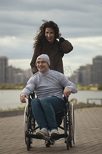 关爱残疾人关爱摄影照片_幸福夫妇的肖像 — 带着轮椅的残疾人的关怀妇女