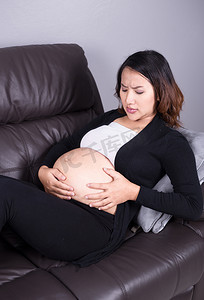 孕妇生病摄影照片_孕妇在客厅宫缩