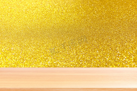 金色灯光背景摄影照片_木板在模糊的金色砂砾散景灯闪耀背景，木桌板在抽象背景金色砂砾散景上空，木桌板在金色琥珀色灯光背景上空