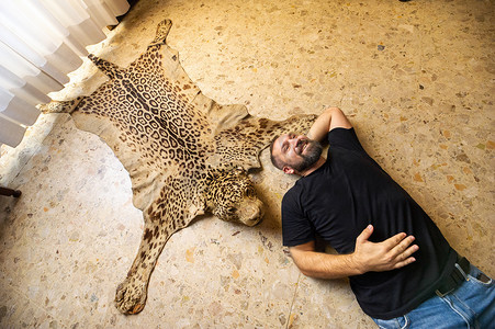 一名男子躺在死豹皮旁的地板上