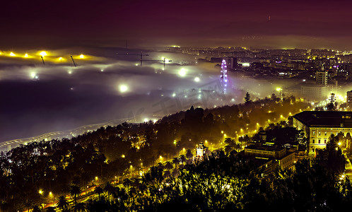 雾子摄影照片_马拉加市雾蒙蒙的夜景，有起重机和摩天轮，Spa