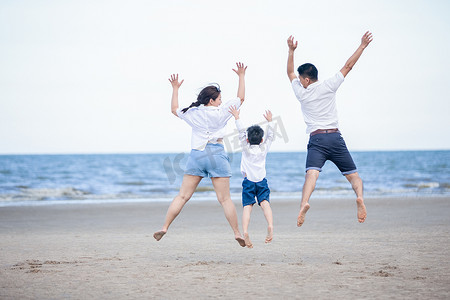 积极的父母和人们在暑假和带孩子的假期进行户外活动。幸福的家庭和儿子在沙滩上享受日落大海的乐趣。