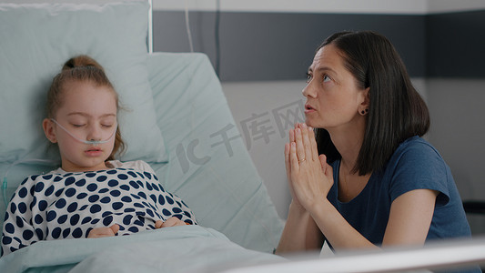 生病的女儿在医疗手术后睡觉，而担心的母亲则祈祷疾病治疗