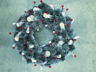 圣诞花环摄影照片_混凝土背景上用松果制成的圣诞花环，冷银色的水平照片
