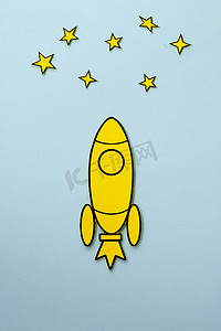 卡通天空摄影照片_蓝色背景上空飞行的黄色卡通火箭