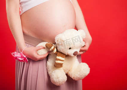 玩具小熊靠在孕妇的肚子上。
