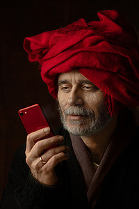 向扬·凡·艾克 (Jan van Eyck) 的画作《戴红色头巾的男人》致敬 - 一张 21 世纪男人的肖像照片，其红色手机与头巾的颜色相匹配