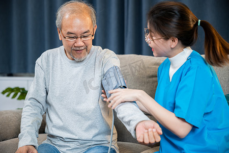 亚洲护士在家探访病人老人，她测量手臂动脉血压