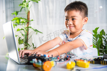亚洲男孩用笔记本电脑为 Arduino 机器人汽车学习编码和编程