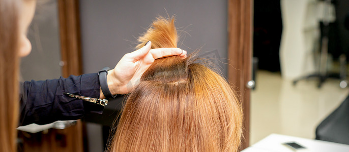 理发师将一缕女性头发夹在手指之间。