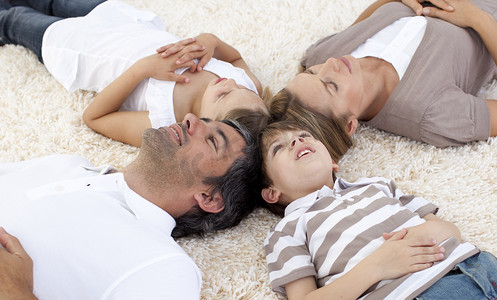 爸爸头摄影照片_一家人躺在家里的地板上，头靠在一起