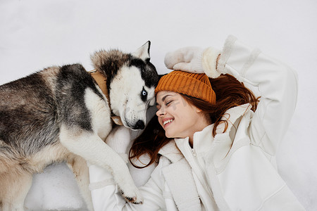 快乐的年轻女人冬装在雪地新鲜空气中遛狗